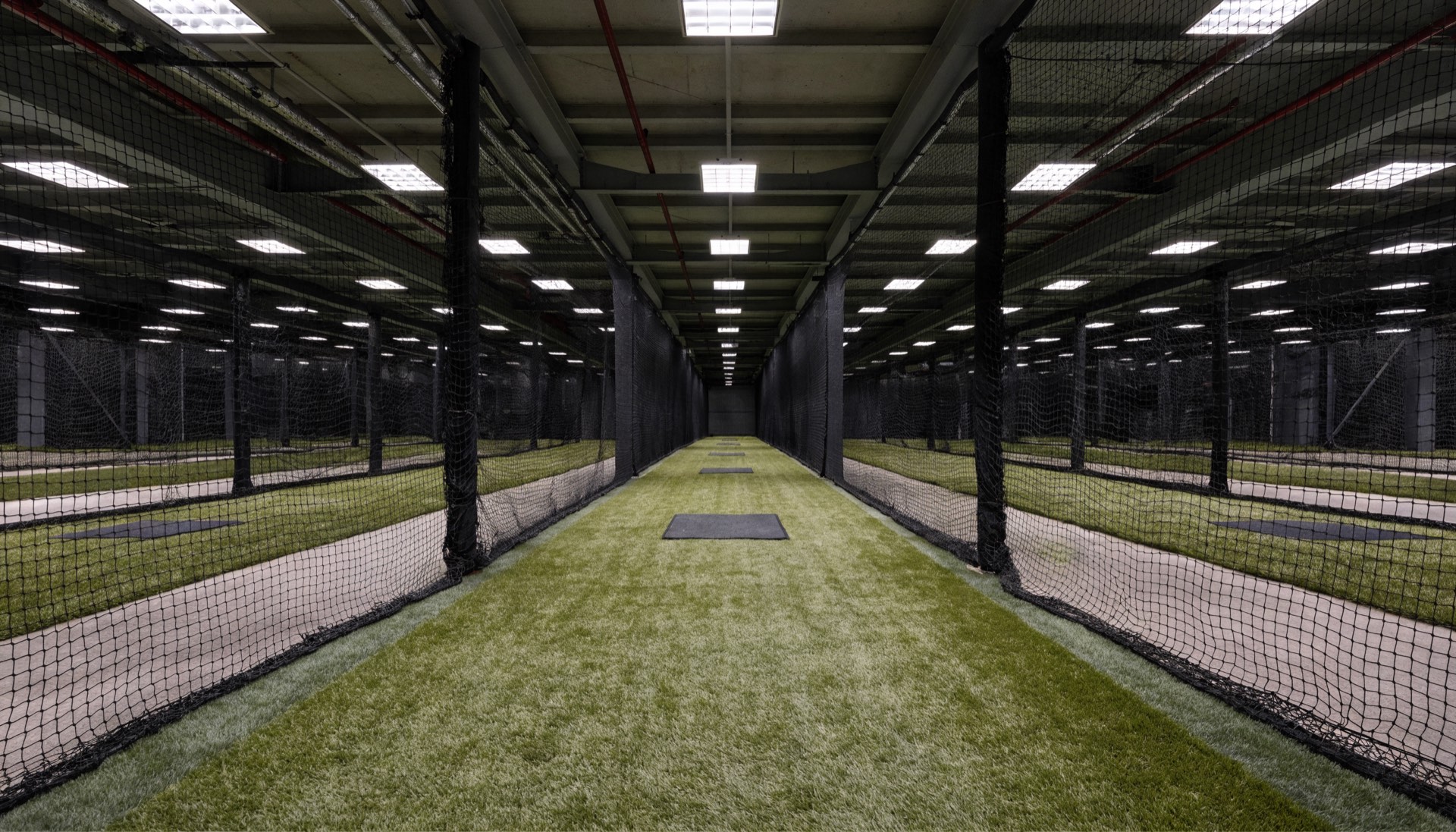 Rows of netted indoor batting tunnels on green turf
